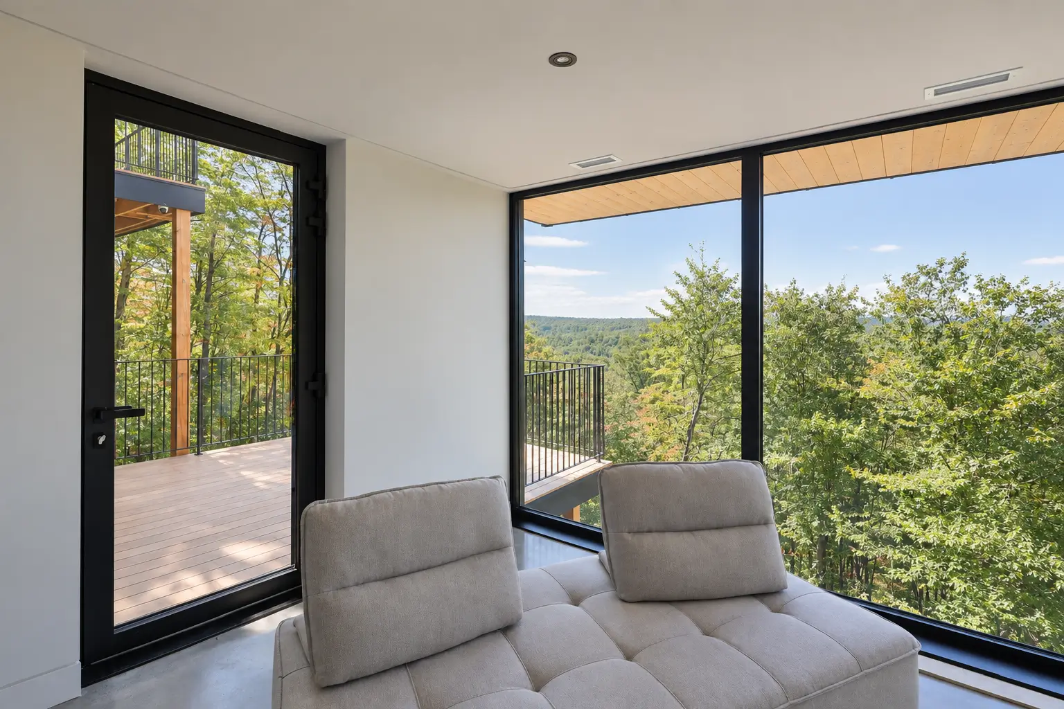 Black-framed glazed door opening onto a deck, beside a large window with a forest view